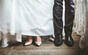 Bride's and groom's shoes side by side on a wooden floor